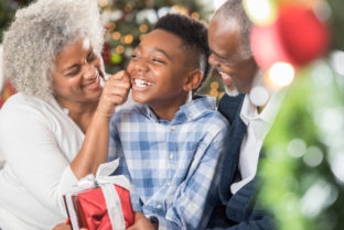 Playful Senior Woman Pinches Her Adorable Grandson's Cheeks At Christmastime.